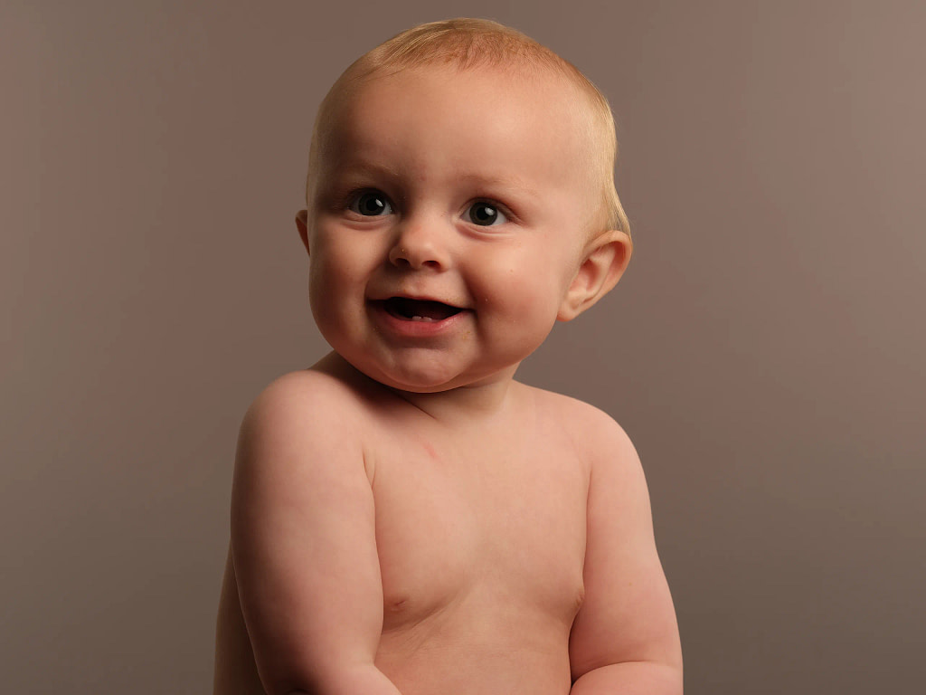 Kids portrait photograph. Three year old boy holds a Gruffalo toy whilst posing in front of a bright, colourful yellow background