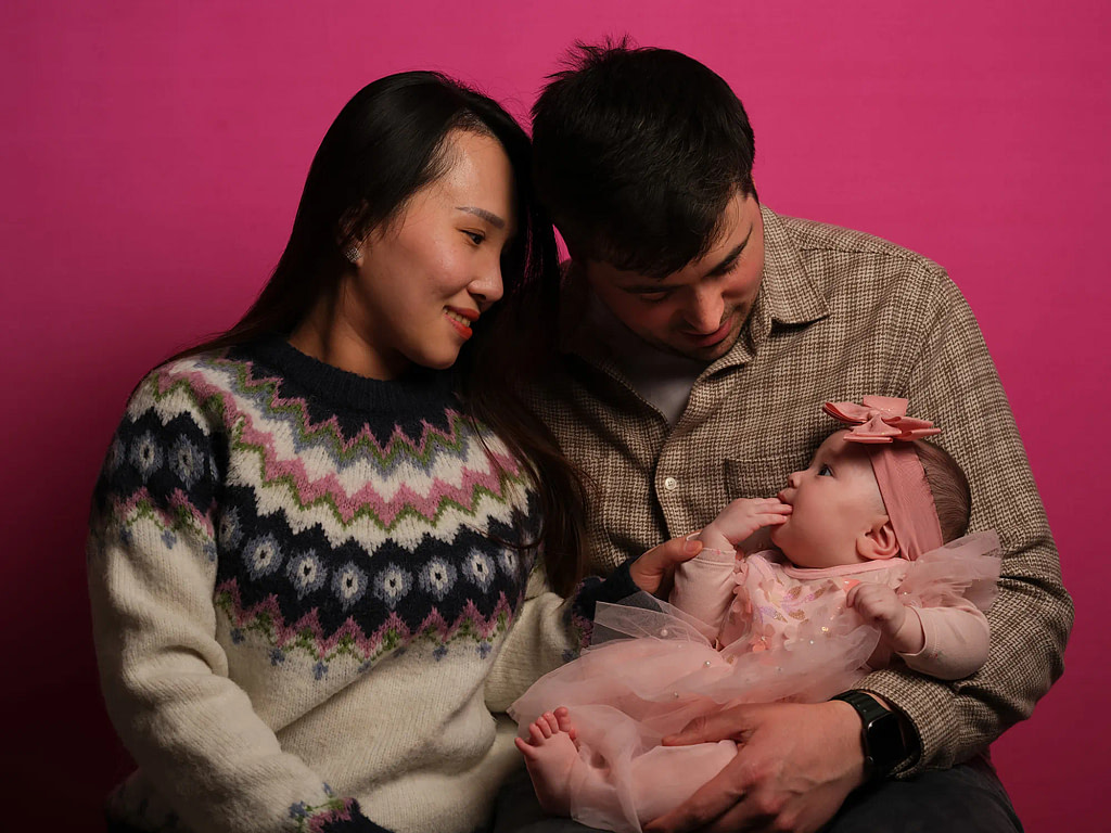 A full family trio portrait taken with the Kaleid 102MP mobile studio, demonstrating how a professional gallery-grade setup fits into a standard living room space.
