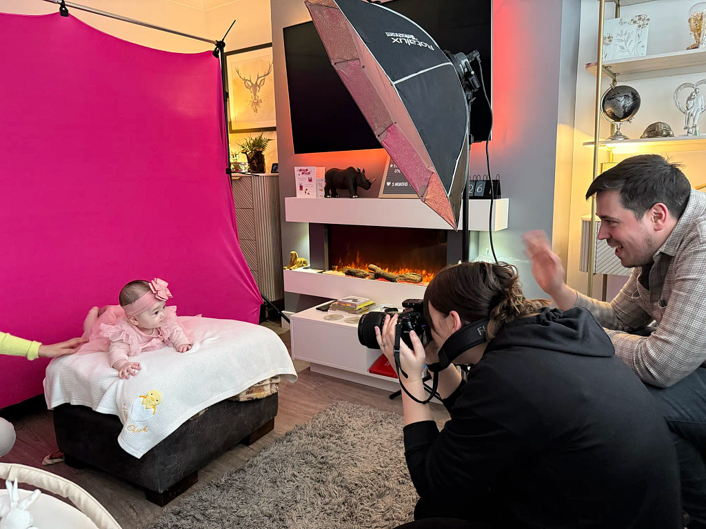 Behind the scenes of a Kaleid mobile portrait studio setup in a small living room with pink backdrop and professional lighting.