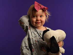 Authentic child portrait of a girl clutching her Snoopy toy, captured in high-detail medium format by Kaleid Studio